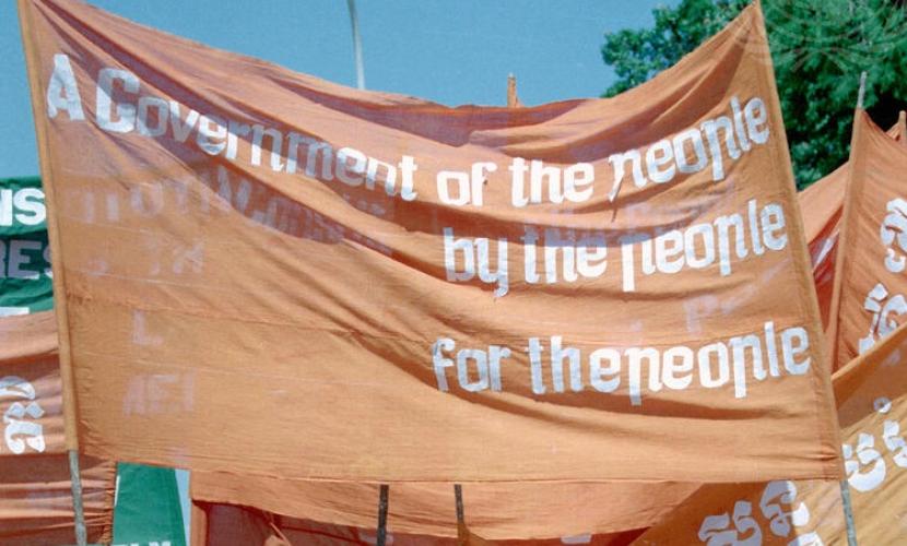 A flag reading "A Government of the people, by the people, for the people"